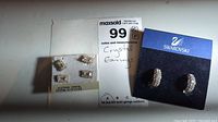 Overview photo showing three sets of crystal earrings including two pairs with rectangular crystals on white cards and one pair of Swarovski brand hoop crystal earrings on blue card.