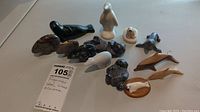Overview of all 13 stone, wood, and ceramic animal figurines on white surface