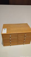 Front view of wooden jewelry box showing six drawers with drop-pull knobs