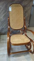 Front view of rocking chair showing wicker seat and backrest with wood frame