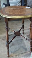 Side view of wooden oval side table showing turned legs and stretcher supports