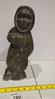 Full front view of stone carving showing man holding a fish with measuring tape for scale.