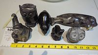 Group photo showing 7 handcrafted stone animal figurines including owl, seal, bear, polar bear, eagle, fish, and small bird, with measuring tape for scale.