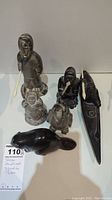 Group photo of six handcrafted stone figurines signed by Thorn, including human and animal figures.