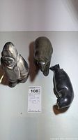 Photo of three stone animal figurines including a figure of an inukshuk, a walrus, and a seal with a note indicating the items are signed by Thorn and handcrafted.