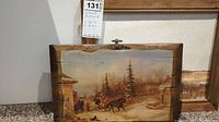 Front view of large wood artwork panel depicting a winter landscape with horse-drawn sleigh and figures outside wooden buildings, showing size and condition.