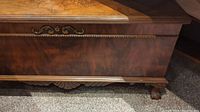 Front and bottom section of wooden chest showing carved decorative accent and claw foot detail.