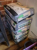Stack of six unopened bags of Custom VersaBond LFT Thin Set Mortar grey color for tile adhesive.
