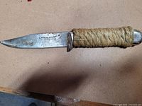 Full view of vintage knife with wrapped handle and metal blade showing wear.