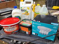 Overall view of household product lot showing pest control, cleaning products and LED bulbs