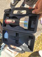 Top view of the zip cutting tool placed inside the black molded plastic carrying case showing handle and body of the tool.