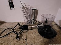 Oster handheld blender motor unit and various attachments spread out on countertop.