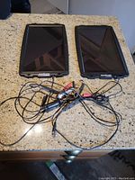 Two solar panel chargers with black casing and multiple cords on a countertop, showing front view.