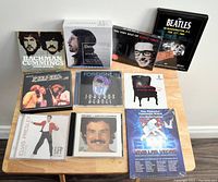 Top-down view of all CDs and DVDs displayed on wooden table, showing front covers and artwork of each item.