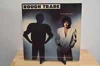 Front cover of Rough Trade 'For Those Who Think Young' vinyl album showing two band members: one dark silhouette with hands on hips, the other a man in a light suit jacket.