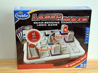 Front of the box showing the game board with laser maze setup and branding