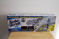 Boxed Turbo Scrub 360 power scrubber showing front packaging, highlighting it as a cordless, handheld, rechargeable power scrubber with multiple brush heads included.