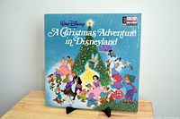 Front cover of Walt Disney Presents A Christmas Adventure in Disneyland vinyl LP showing classic Disney characters around a Christmas tree on blue background.