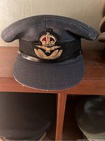 Blue topped Royal Navy hat with black band and embroidered winged emblem with crown on the front