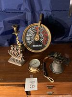 Photo showing the entire lot with the engine order telegraph, candlestick, ship figurine, barometer, bell, and telegraph key arranged on a wooden surface.