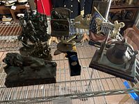 Photo showing wide view of the military and nautical decor items on metal shelving including lion statue, ship figures, flag plaque, and bell