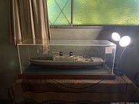 Full view of the replica naval ship President Wilson inside a plexiglass display case on a wooden base.