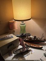 Photo showing ship models prominently with two lamps and a storage box visible