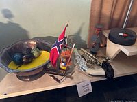 Shot showing the decorative bowl with polished stones, miniature boat with Norwegian flag, decorative pistol, and fisherman figurine arranged together
