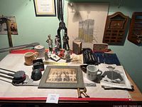 Overview of the lot showing array of military statues, mugs, framed photo, and other items on a tabletop.