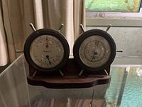 Front view of dual gauge unit on wooden stand showing barometer and temperature/humidity