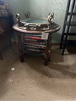 Full view of the nautical themed round wooden table with glass top and brass porthole framing with several hardcover books stacked inside the table base.