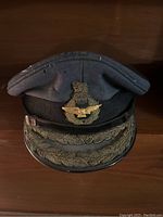 Front view of the RAF peaked cap showing badge, fabric, and embroidered visor.