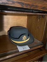Exterior view of the green U.S. Army women's service hat showing the gold embroidered eagle emblem and gold trim on the crown.