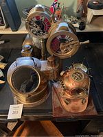 Two engine order telegraphs side by side on stands, plus lamp chimney and porthole housing at front