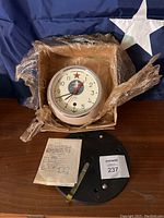Clock in original packaging with mounting bracket and paperwork laid out.