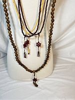 Front view of the four malas displayed on a torso mannequin showing bead color and tassels.