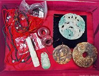 Overview of the 7 jade jewelry pieces arranged in a red display box showing variety of carved pendants and beads