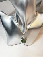 Front view of dragon claw gemstone pendant necklace displayed on silver mannequin bust.
