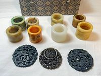 Full set top-down view showing 6 archer rings in varied stone colors and 3 black green jade carved pendants.