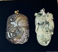 Photo of two jade pendants displayed side by side on black background showing color, texture and carvings.