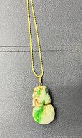 Front view of the vintage Chinese necklace showing the carved jade pendant with natural green and brown colors on a gold plated chain.