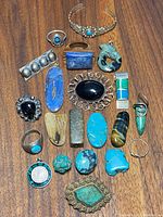 Overview of collection on wood surface showing cuff, rings, brooches, pendants, and loose stones