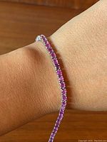 Bracelet on wrist showing single row of pink-red rubies set in sterling silver.