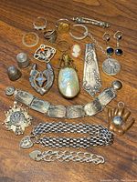 Overview of rings, thimbles, pendants, cufflinks, brooches and bracelets on wooden surface