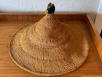 Front view of entire conical woven hat on wooden surface