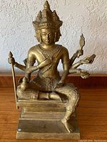 Full frontal view of seated brass Buddhist deity on rectangular base