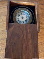Top-down photo showing the compass inside the wooden box with the sliding lid partially open.
