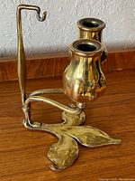 Three-quarter front view showing dual candle cups, leaf base and handle