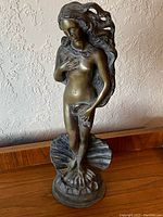 Front view of full sculpture on wood surface against textured wall