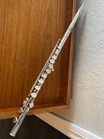 Full assembled flute leaning against wooden backdrop